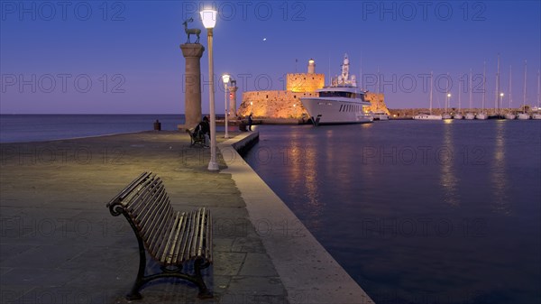 Quiet harbour promenade with bench and lamppost opposite fort and boats in moonlight, night shot, Deer statue, luxury yacht, Fort of Saint Nikolaos, harbour promenade, Rhodes, Dodecanese, Greek Islands, Greece, Europe
