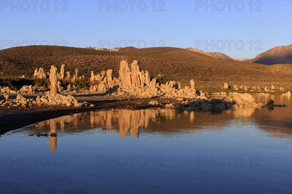 Warm sunset light on tufa towers at Mono Lake with calm water reflection, Mono Lake, North America, USA, South-West, California, California, North America