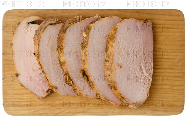 Top view of wooden cutting board with sliced baked pork fillet
