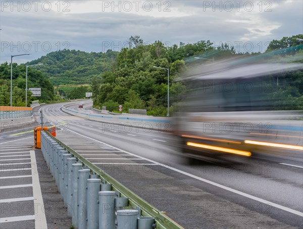 Streaks of light and blur of passing vehicle on highway in countryside location during blue hour under cloudy skies in South Korea