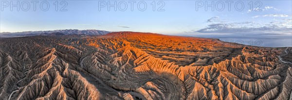 Canyon runs through landscape, Issyk Kul Lake, behind white peaks of the Tien Shan Mountains, Dramatic barren landscape of eroded hills, Badlands, Canyon of the Forgotten Rivers, Issyk Kul, Kyrgyzstan, Asia