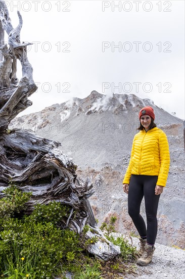 Young woman in yellow jacket standing in front of a volcano, Chaiten Volcano, Carretara Austral, Chile, South America