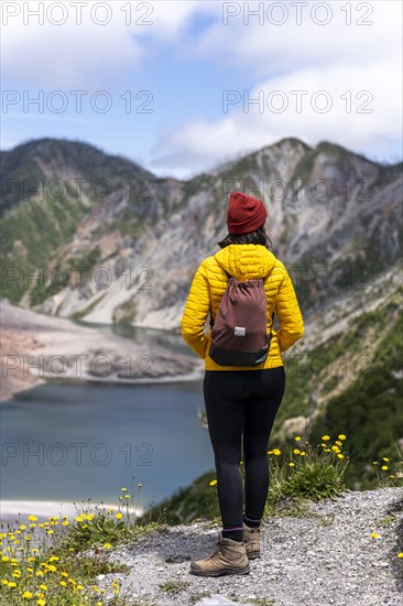 Young woman in yellow jacket standing in front of a volcano, Chaiten Volcano, Carretara Austral, Chile, South America