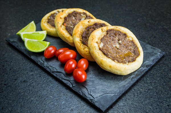 Delicious Lebanese (Arabic) food, genuine sfihas on a slate plate with tomatoes and lemons
