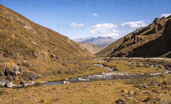 Autumn mountain landscape with yellow grass, mountain stream at Ak-Tog Pass, road to Karkyra Valley, Kyrgyzstan, Asia