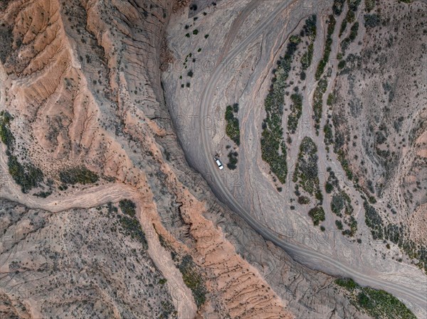 Aerial view, 4x4 car, Camping in dry riverbed, View from above, Canyon runs through landscape, Dramatic barren landscape of eroded hills, Badlands, Canyon of the Forgotten Rivers, Issyk Kul, Kyrgyzstan, Asia