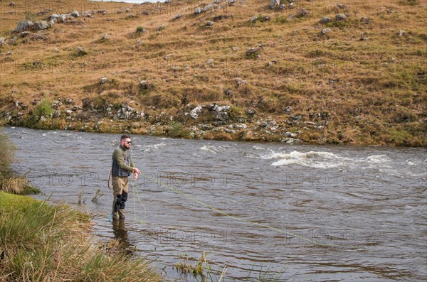 Fisherman fly fishing rainbow trout on mountain in beautiful scenery