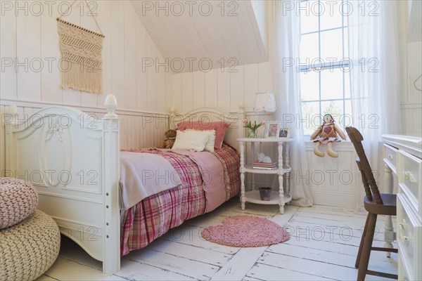 Single bed with red, pink and grey tartan bedspread, white painted antique style wooden headboard and footboard, nightstand, dresser with brown chair in a kid's bedroom with white painted larch wood floorboards on upstairs floor inside country style home, Quebec, Canada, North America