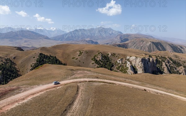 Moldo-Ashuu Pass, car on road between yellow hills, near Baetov, Naryn region, Kyrgyzstan, Asia