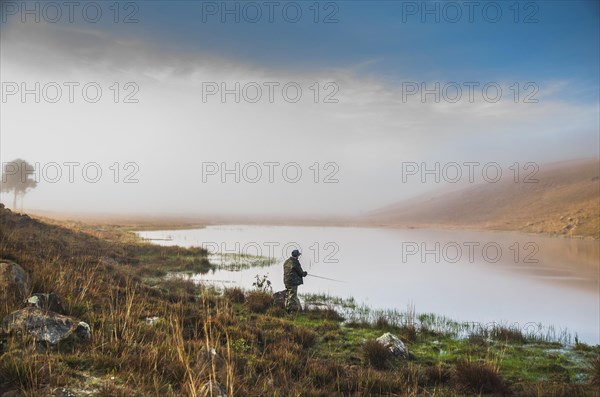 Sport fisherman fishing in lake on cloudy day, Cambara do sul, Rio Grande do sul, Brazil, South America