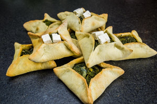 Delicious Lebanese (Arabic) food, spinach sfiha with ricotta cheese on black stone background