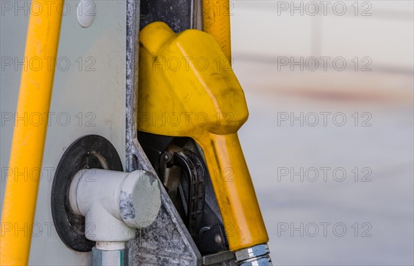 Closeup of gas pump handle with yellow rubberized cover inserted into side of gas pump in South Korea
