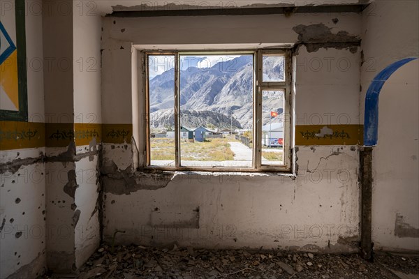 View through a window onto the mountain landscape, abandoned destroyed room with colourful wall painting, ghost town, Engilchek, Tian Shan, Kyrgyzstan, Asia