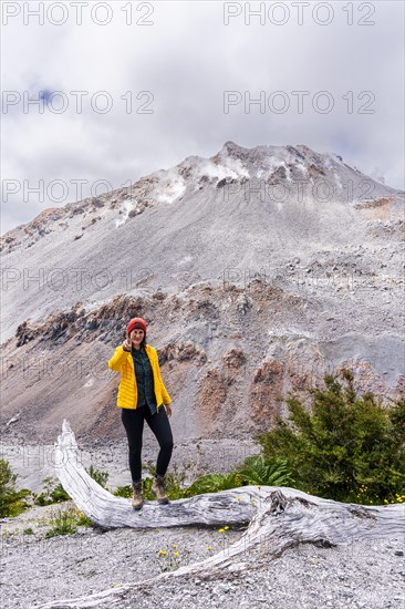 Young woman in yellow jacket standing in front of a volcano, Chaiten Volcano, Carretara Austral, Chile, South America