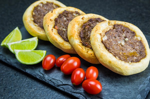 Delicious Lebanese (Arabic) food, genuine sfihas on a slate plate with tomatoes and lemons