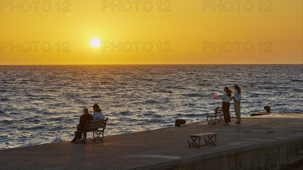 People relaxing on the shore and enjoying the sunset over the sea, dusk, sunset, Western Promenade, Rhodes Town, Rhodes, Dodecanese, Greek Islands, Greece, Europe