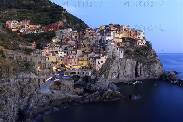 Dusk falls on Manarola and sets the colourful houses and the festive lighting in the right light, Italy, Liguria, Manarola, Riomaggiore, La Spezia Province, Cinque Terre, Europe