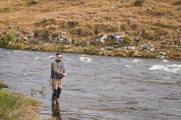 Fisherman fly fishing rainbow trout on mountain in beautiful scenery