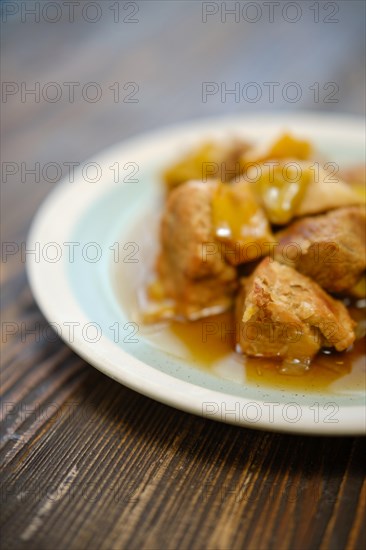 Top view of plate with pork and vegetables ragout on wooden background