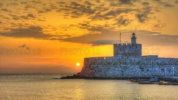 A lighthouse on a fortress wall by the sea during a colourful sunrise, sunrise, dawn, lighthouse, Fort of Saint Nikolaos, harbour promenade, Rhodes, Dodecanese, Greek Islands, Greece, Europe