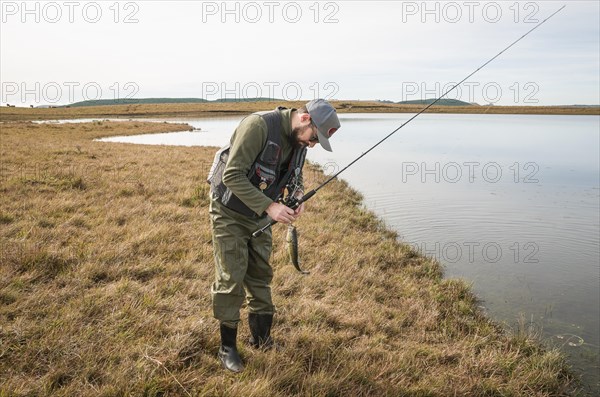 Sport fisherman fishing in lake on cloudy day, Cambara do sul, Rio Grande do sul, Brazil, South America