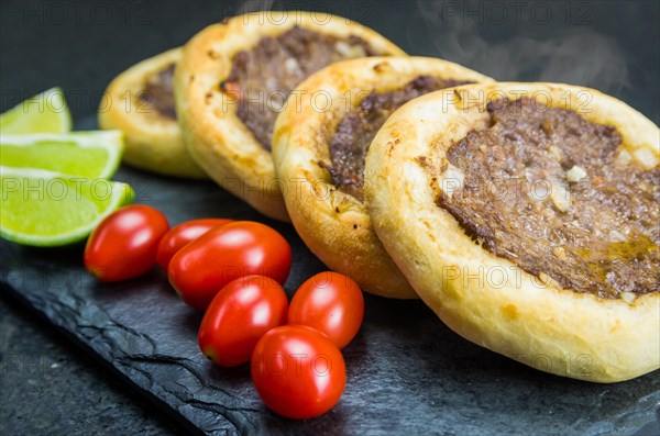 Delicious Lebanese (Arabic) food, genuine sfihas on a slate plate with tomatoes and lemons