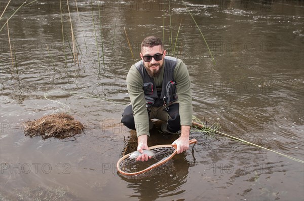 Fisherman fly fishing rainbow trout on mountain in beautiful scenery