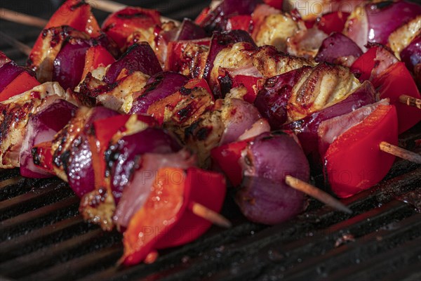 Grilled skewers with Sweet peppers, onions and pieces of chicken on a charcoal grill with visible grill marks