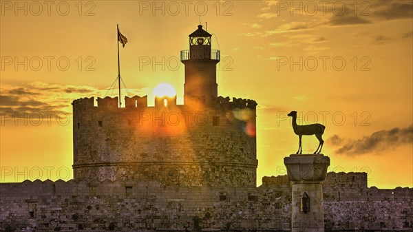 Warm sunlight shines through the windows of a lighthouse on an old castle wall, sunrise, dawn, European roe deer statue, Fort of Saint Nikolaos, harbour promenade, Rhodes, Dodecanese, Greek Islands, Greece, Europe