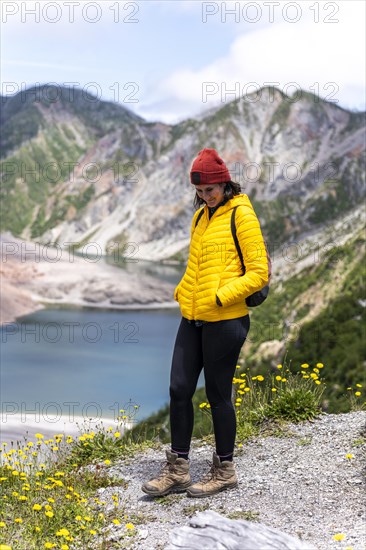 Young woman in yellow jacket standing in front of a volcano, Chaiten Volcano, Carretara Austral, Chile, South America