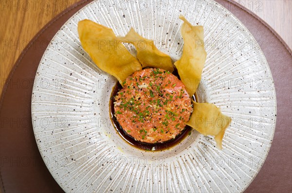 PERUVIAN FOOD. Spiced Salmon Ceviche with Chives and Lime on a white plate served with Fried Sweet Potato Wedges