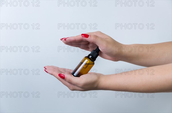 Product package with serum and a woman hand in studio on a background to promote an antiaging treatment. Skincare, beauty and bottle with a female model. Mockup