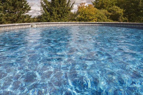 Above ground swimming pool surrounded by deciduous trees in residential backyard, Quebec, Canada, North America