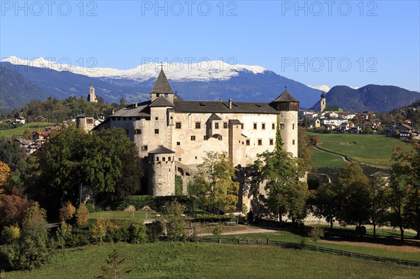 A castle surrounded by autumn trees and green meadows against a mountain background, Italy, Trentino-Alto Adige, Alto Adige, Bolzano province, Dolomites, Proesels Castle, Europe