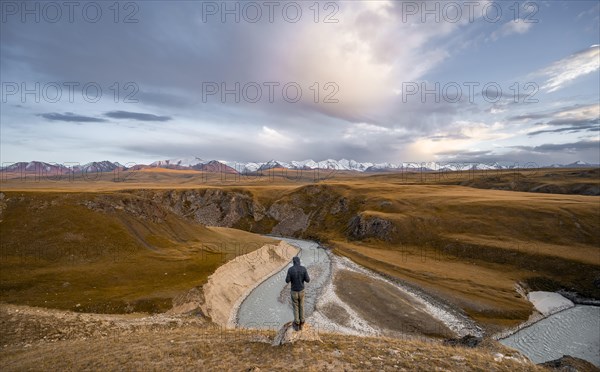 Tourist looking into the distance, mountain valley with Sary Jaz river, high glaciated mountain peaks of the Tien Shan in the background, autumn mountains with yellow grass, Tien Shan, Kyrgyzstan, Asia