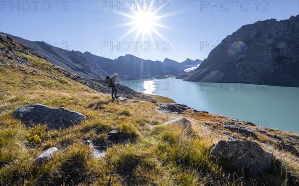 Mountaineers at the turquoise Ala Kul mountain lake in the morning light, Sun Star, Tien Shan Mountains, Kyrgyzstan, Asia