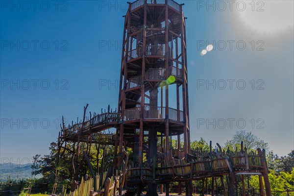 Wooden observation tower with winding staircase on top of mountain on sunny day with blue sky in South Korea