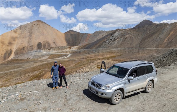 Two tourists with car at the mountain pass in Tien Shan, Chong Ashuu Pass, Kyrgyzstan, Issyk Kul, Kyrgyzstan, Asia