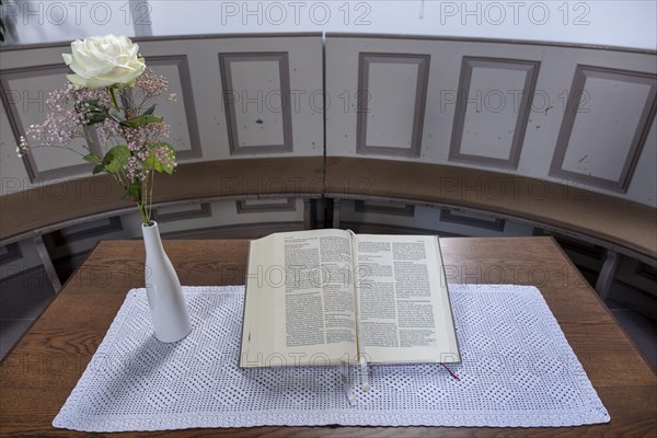 Open Bible next to a vase of flowers with a white Rose in the Protestant Reformed Church from 1401 in Greetsiel, Krummhoern, East Frisia, Lower Saxony, Germany, Europe
