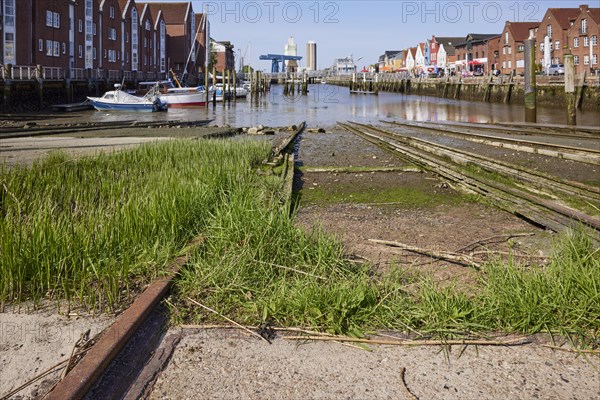 Old rusty rails with grass of the slipway of the old shipyard in the harbour of Husum, district of Nordfriesland, Schleswig-Holstein, Germany, Europe