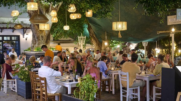 People dining in the evening in a cosy outdoor restaurant under lanterns, night shot, Rhodes Old Town, Rhodes, Dodecanese, Greek Islands, Greece, Europe