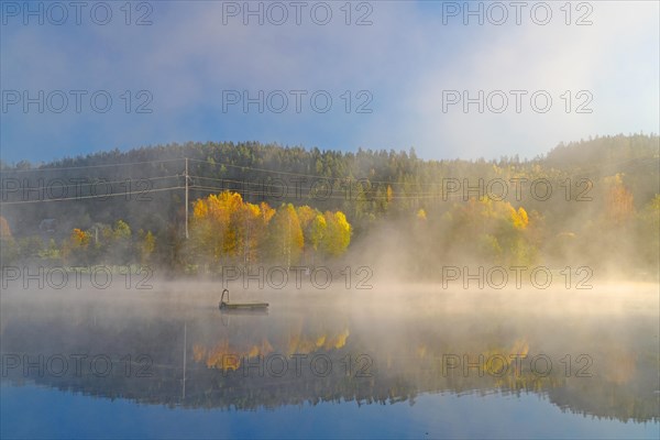 Sunrise and autumn morning mist over a calm lake, bathing island, foliage colouring, Bullaren, Bohuslaen. Sweden