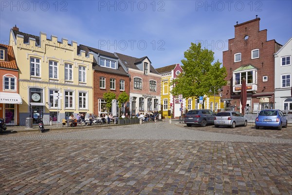 Restaurant and houses with colourful facades and a street of cobblestones in the harbour of Husum, Nordfriesland district, Schleswig-Holstein, Germany, Europe