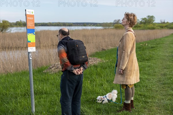 Man and woman reading sign, information board, dog, Elbtalaue near Bleckede, Lower Saxony, Germany, Europe
