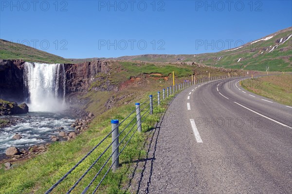 Waterfall in front of a road winding up the mountain, Gufufoss, Seydisfjoerdur, Iceland, Europe