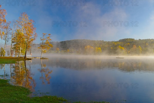 Sunrise and autumnal morning mist over a calm lake, foliage colouring, Bullaren, Bohuslaen. Sweden