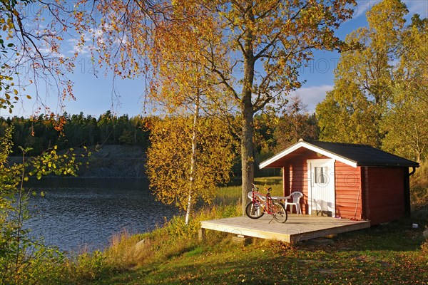 Small hut and a bicycle by a lake, foliage colouring, holiday mood, Hoegbyn, Dalsland Canal, Sweden, Europe