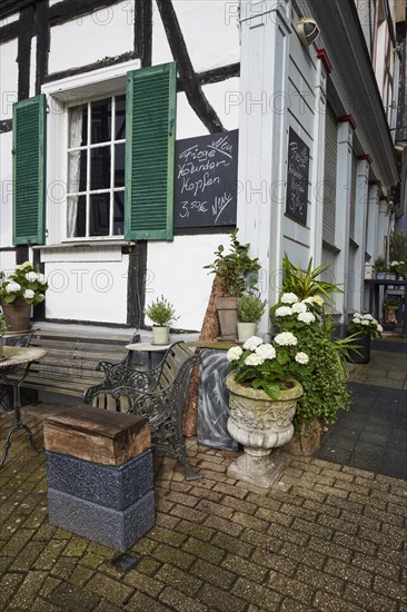 Wooden bench and small table with flowers at a cafe in Hattingen, Ennepe-Ruhr-Kreis, North Rhine-Westphalia, Germany, Europe