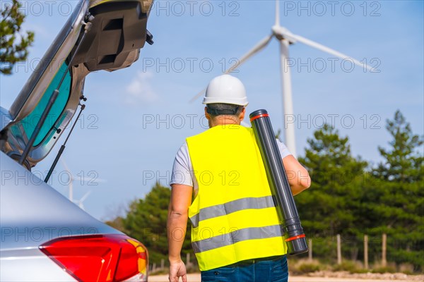 Rear view of a male worker with drawing tube walking along a wind energy park