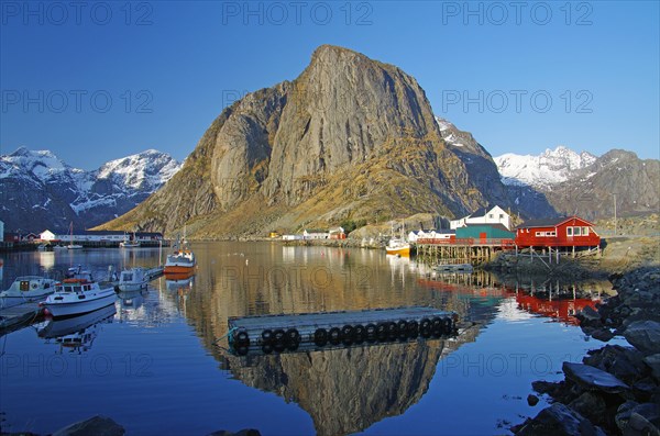 Barren mountains and red houses reflected in the calm waters of a fjord, winter, Hamnoey, Lofoten, Nordland, Norway, Europe